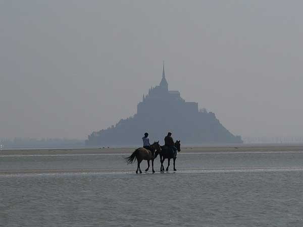 Dos personas cabalgando hacia el Mont Saint Michel
